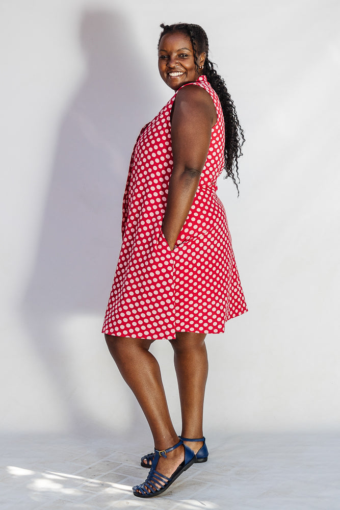 Model wearing red sleeveless dress with white dots.