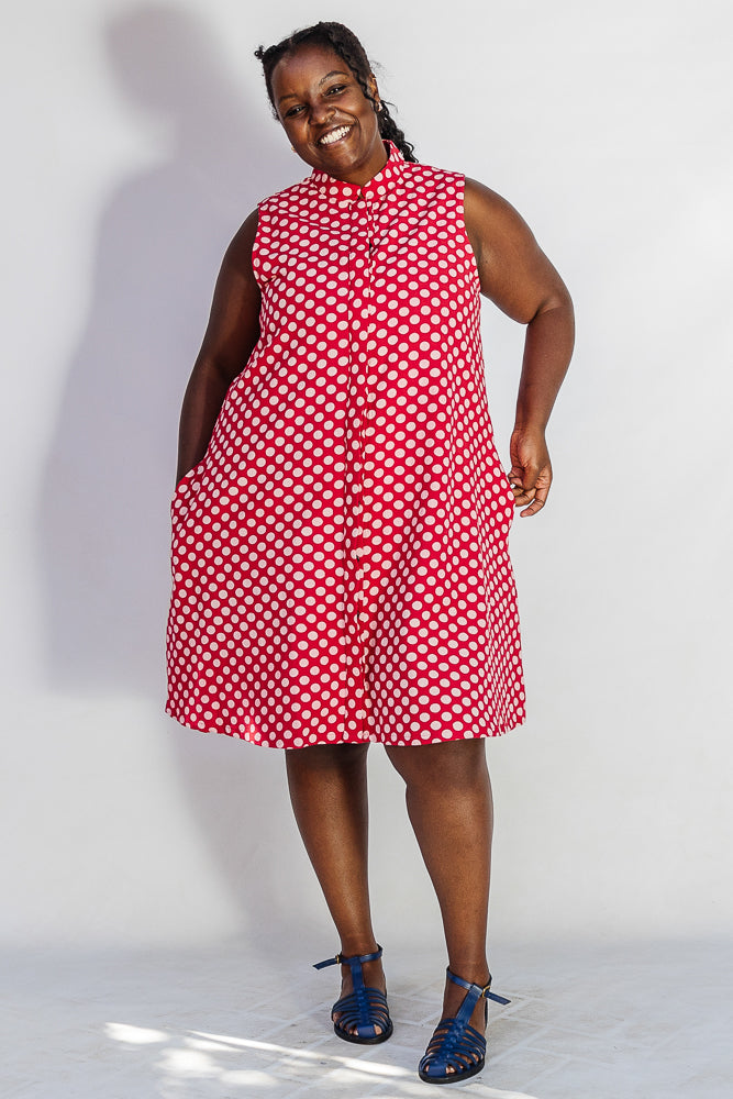 Model wearing red sleeveless dress with white dots.