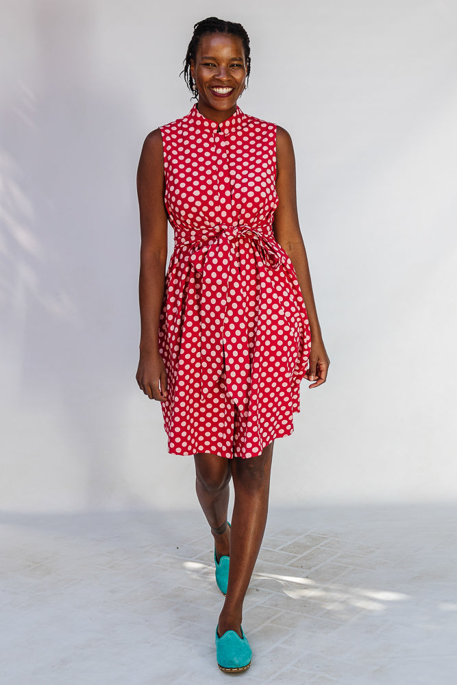 Model wearing red sleeveless dress with white dots.
