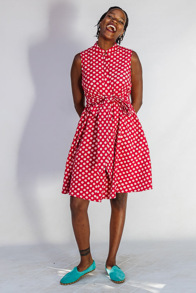 Model wearing red sleeveless dress with white dots.
