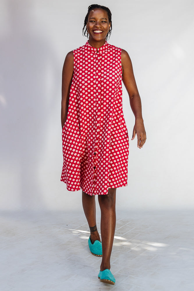 Model wearing red sleeveless dress with white dots.
