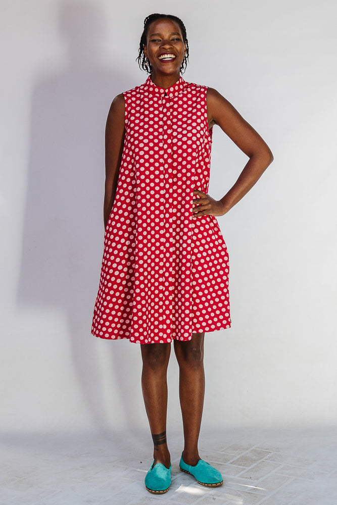 Model wearing red sleeveless dress with white dots.