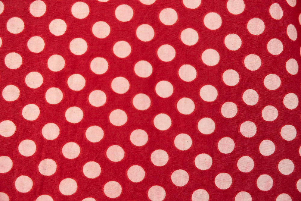 Close up display of red sleeveless dress with white dots, fabric.