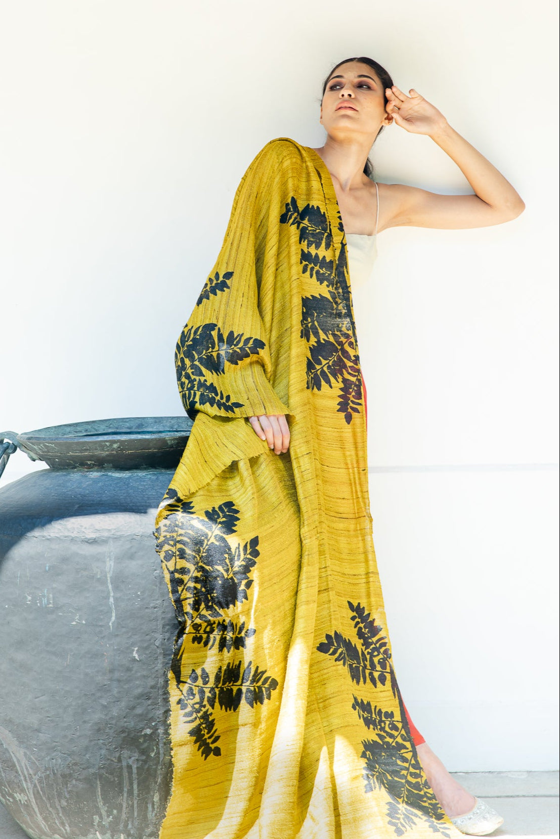 A person holding a peace silk scarf with a floral pattern, displayed in a light-colored fabric.
