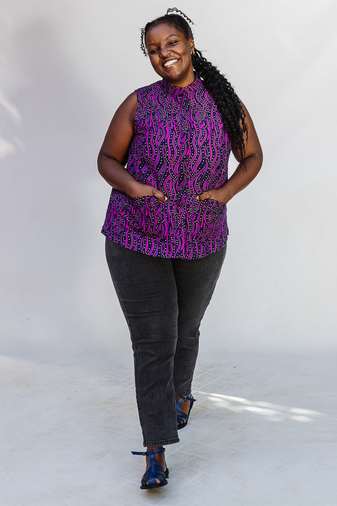 Model wearing purple and black abstract print sleeveless shirt.