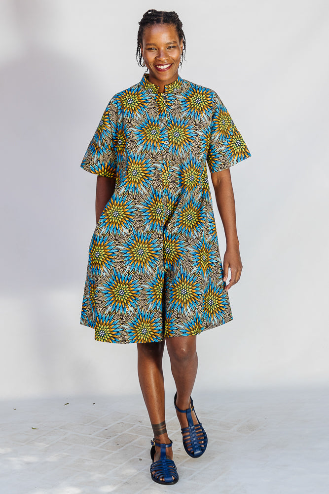 Model wearing blue, yellow, orange and black geometric print dress.