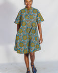 Model wearing blue, yellow, orange and black geometric print dress.