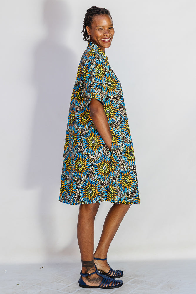 Model wearing blue, yellow, orange and black geometric print dress.