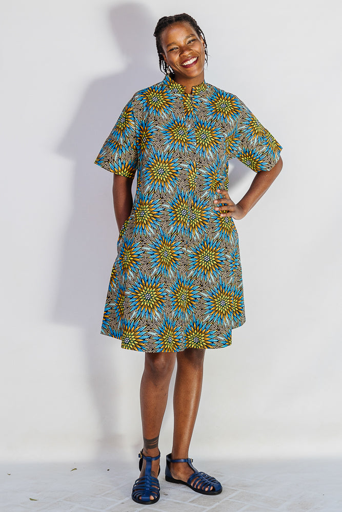 Model wearing blue, yellow, orange and black geometric print dress.