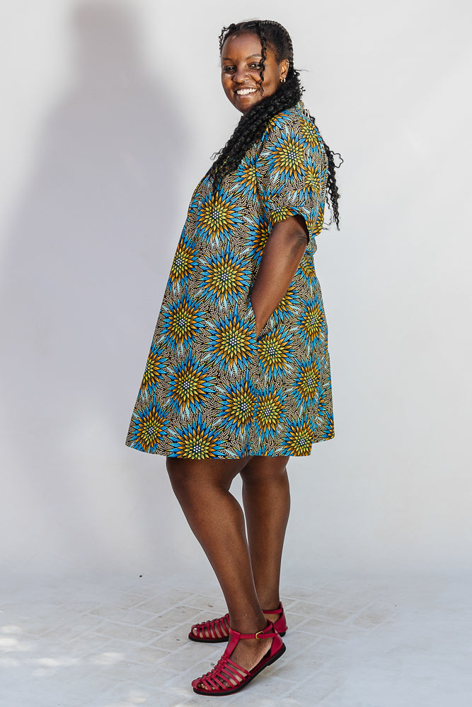 Model wearing blue, yellow, orange and black geometric print dress.