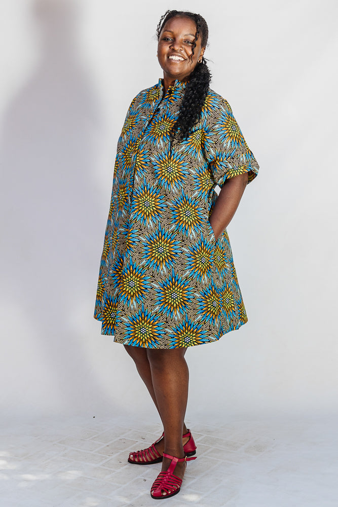 Model wearing blue, yellow, orange and black geometric print dress.