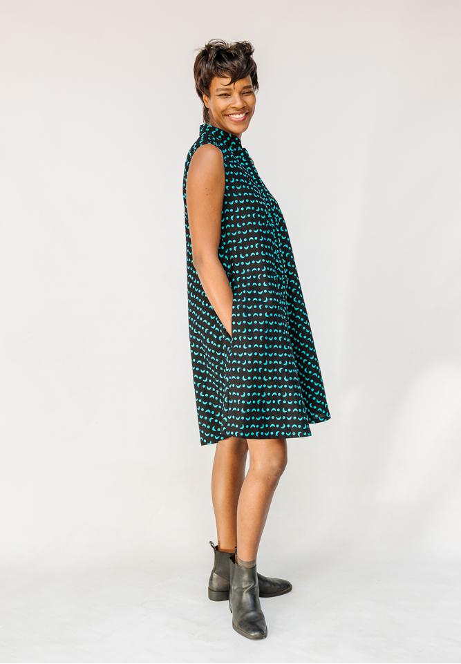 Model wearing sleeveless black dress with teal moon design.