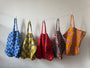 Colorful patterned bags hanging on a line against a white wall