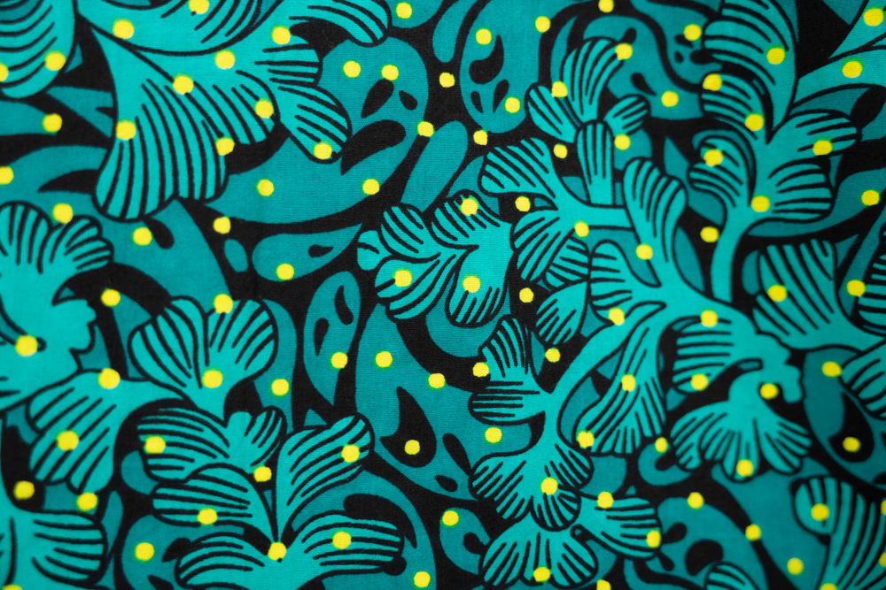 Close up display of teal, black and yellow floral print sleeveless shirt, fabric.