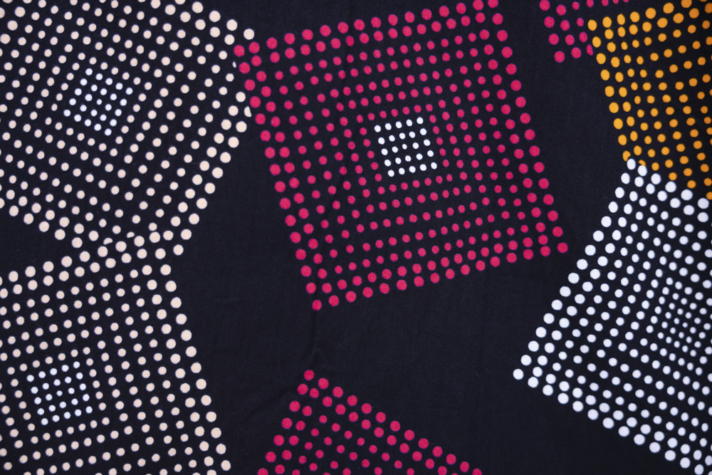 Close up display of pink, orange, white and black geometric print dress, fabric.