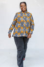 Model wearing blue, white and yellow abstract print shirt.