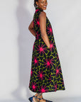 Model wearing navy and green dress with pink floral print.
