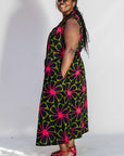Model wearing navy and green dress with pink floral print.