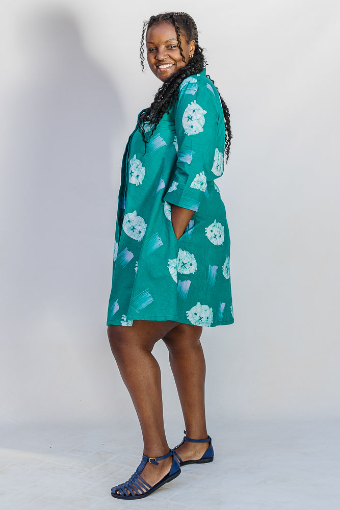 Model wearing teal dress with white cat print.
