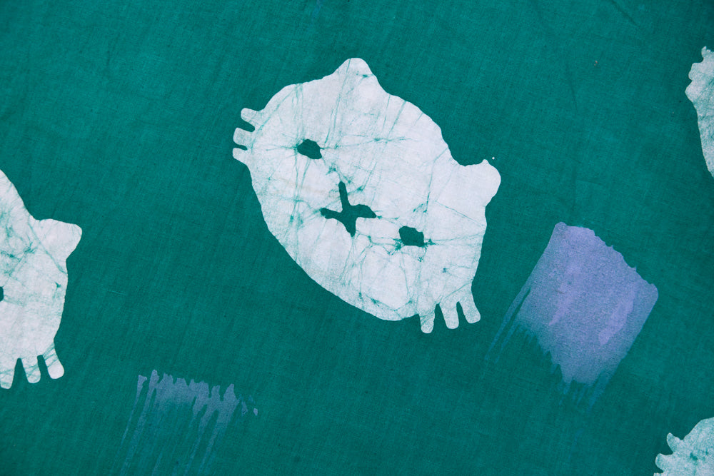 Close up display of teal dress with white cat print, fabric.