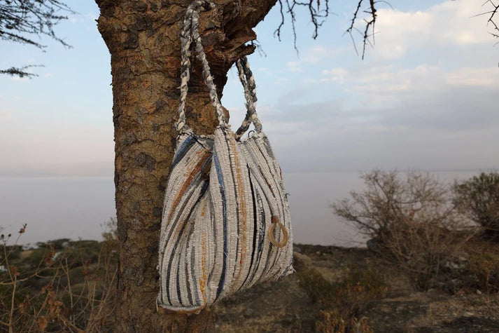 Striped handbag hanging from a tree in a natural setting
