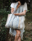 Person holding a patterned tote bag in a natural setting