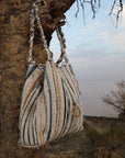 Striped handbag hanging from a tree in a natural setting
