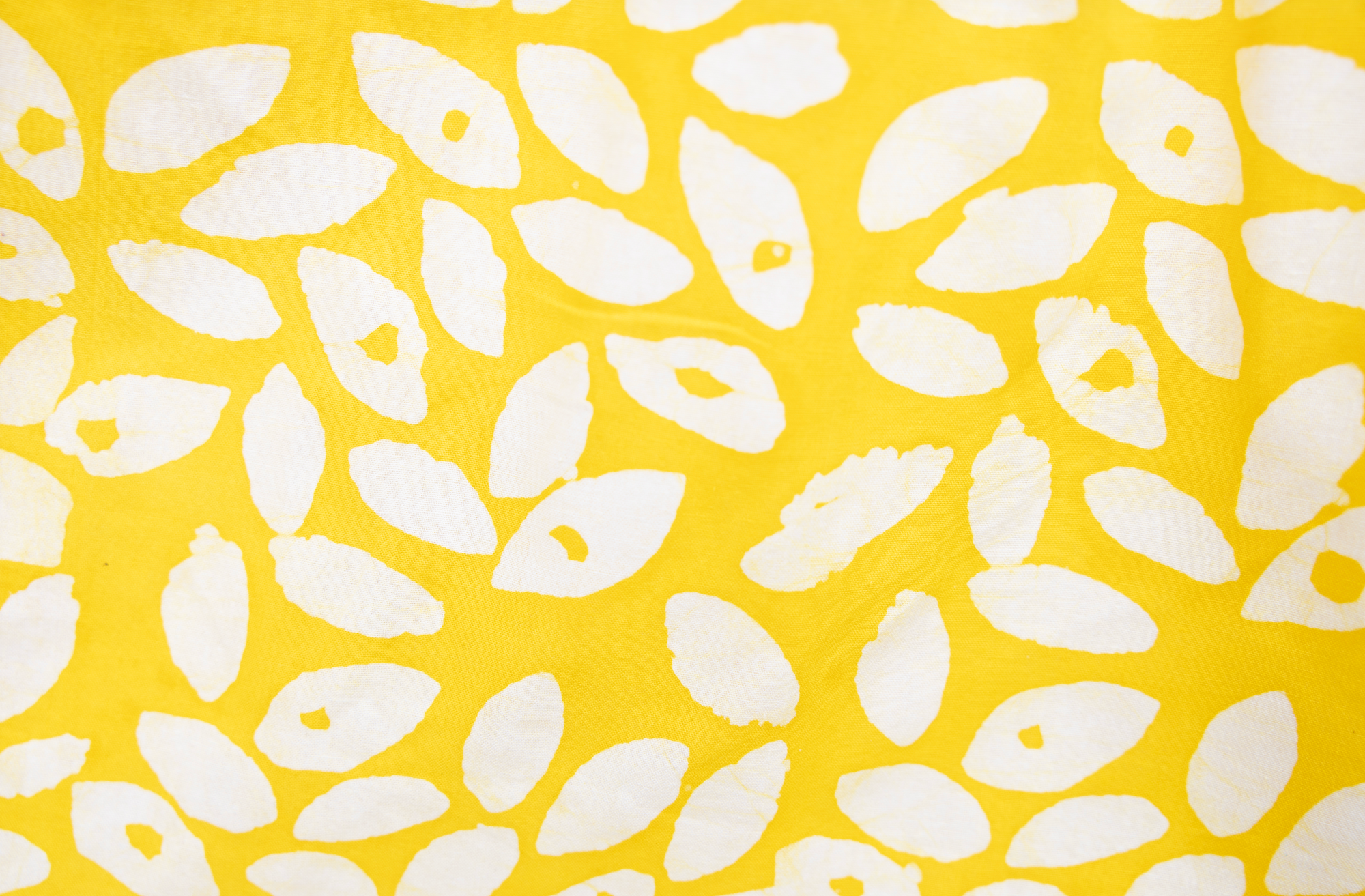 Close up display of yellow long sleeve shirt with white leaf print, fabric.
