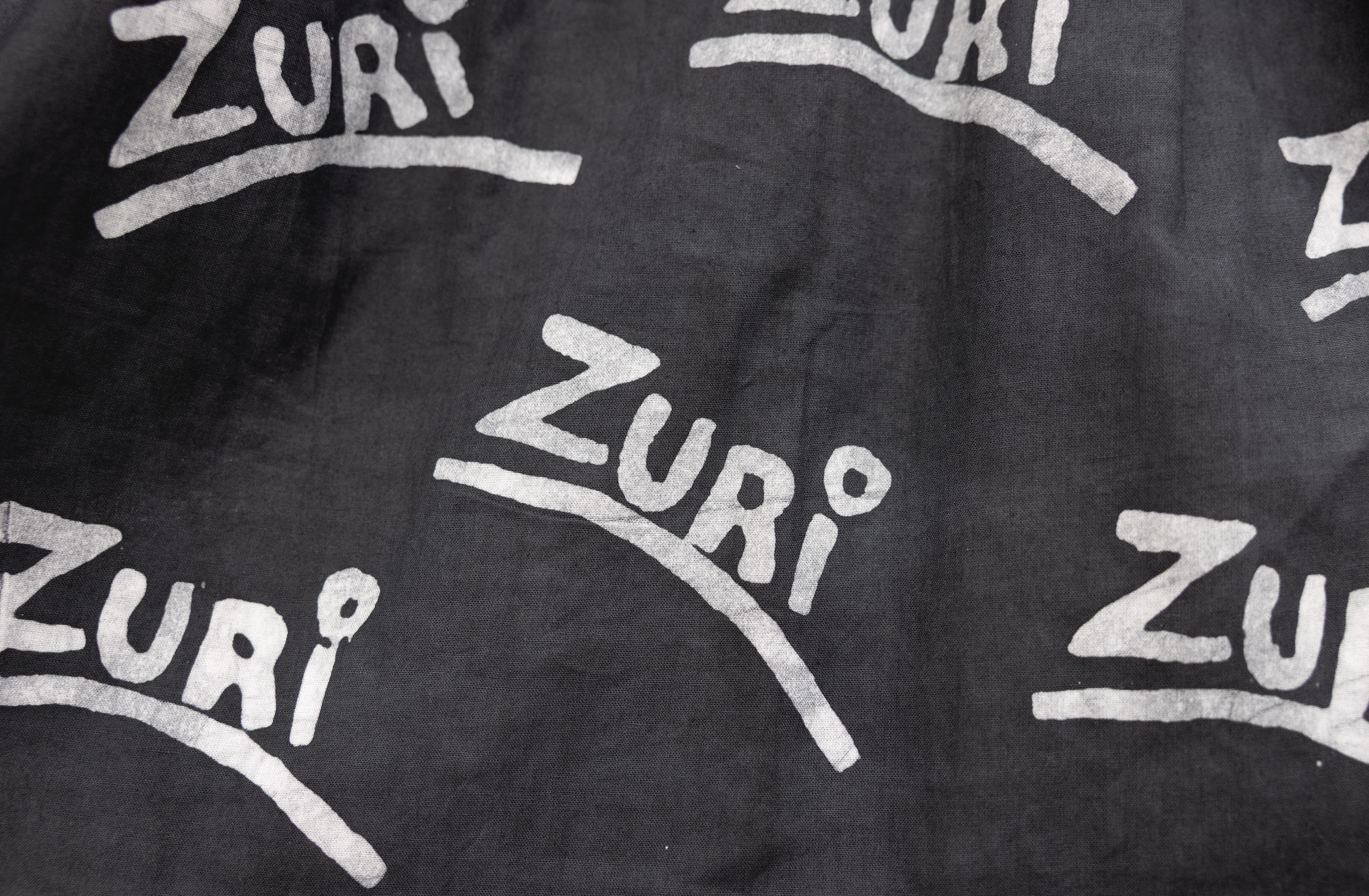 Close up display of black and white long sleeve shirt with Zuri graphic print, fabric.