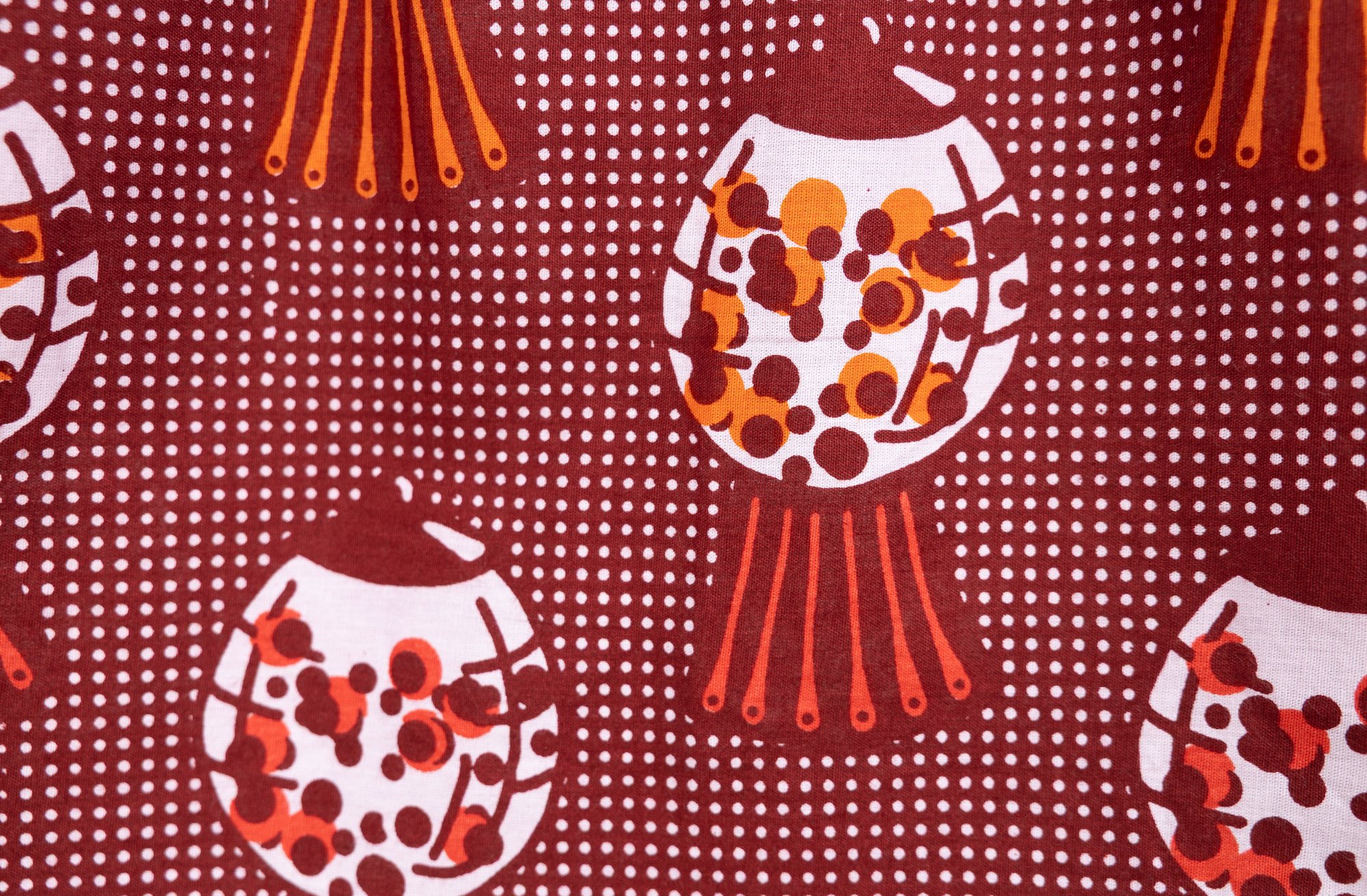 Close up display of red shirt with orange and white gumball print, fabric.