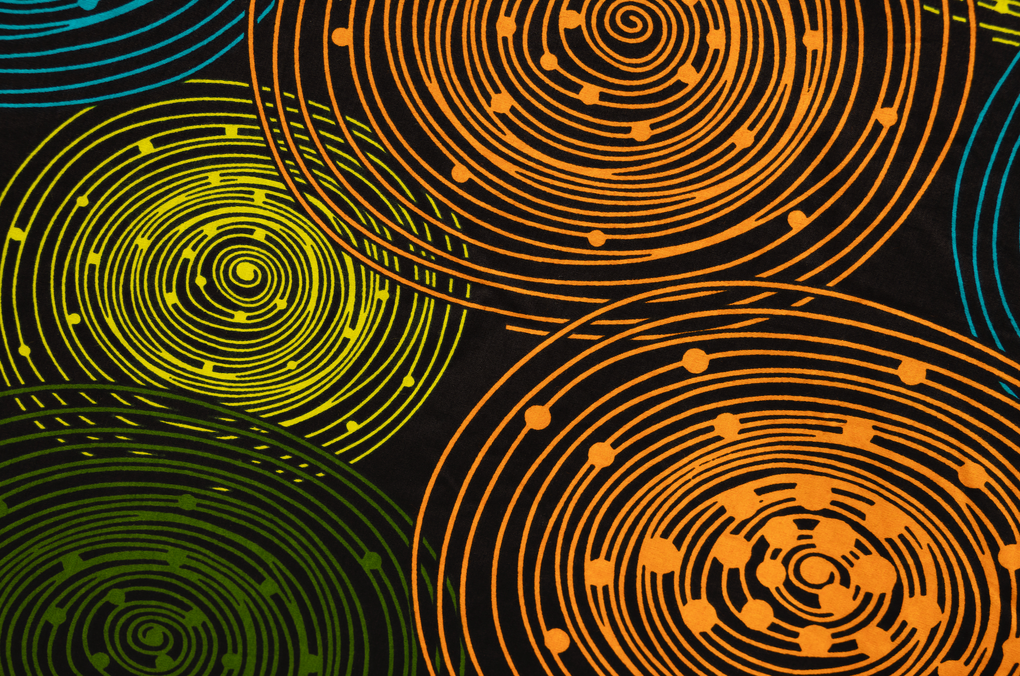 Close up display of black dress with orange, yellow, blue and green swirls, fabric.