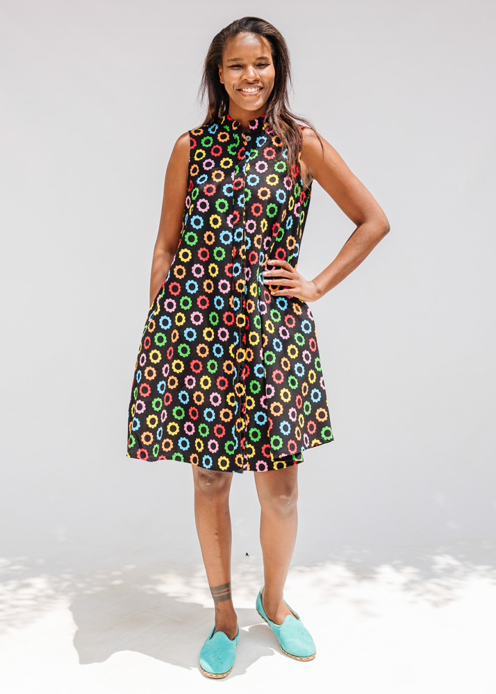 Model wearing black sleeveless dress with rainbow circle print.