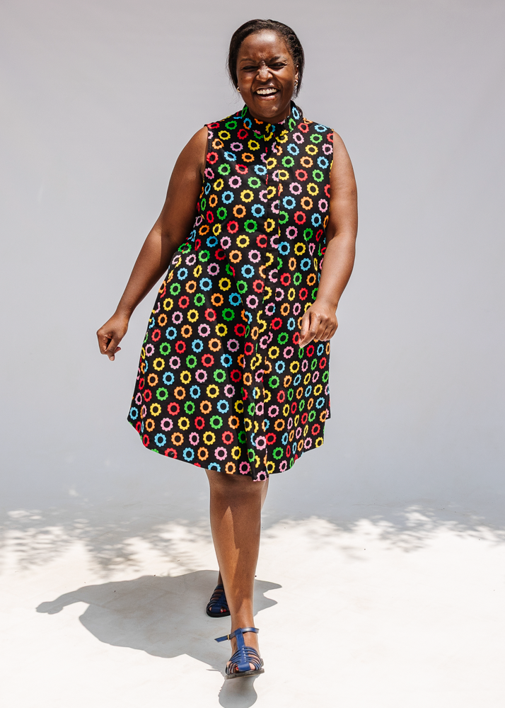 Model wearing black sleeveless dress with rainbow circle print.