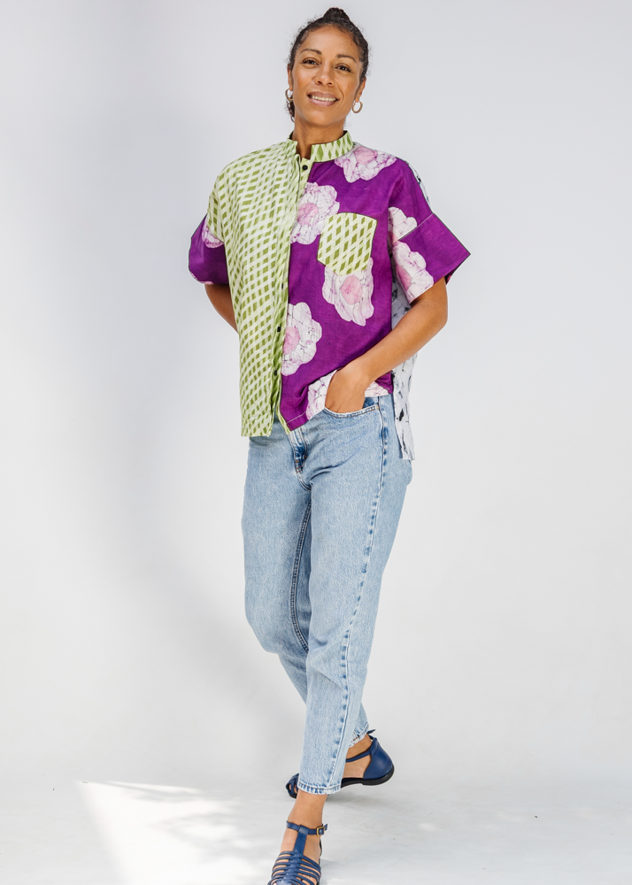Woman wearing a colorful patterned shirt and jeans on a white background