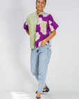 Woman wearing a colorful patterned shirt and jeans on a white background