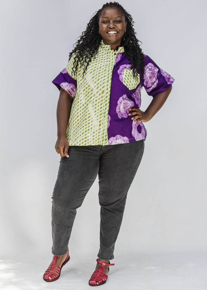 Woman wearing a colorful patterned shirt and gray pants on a white background