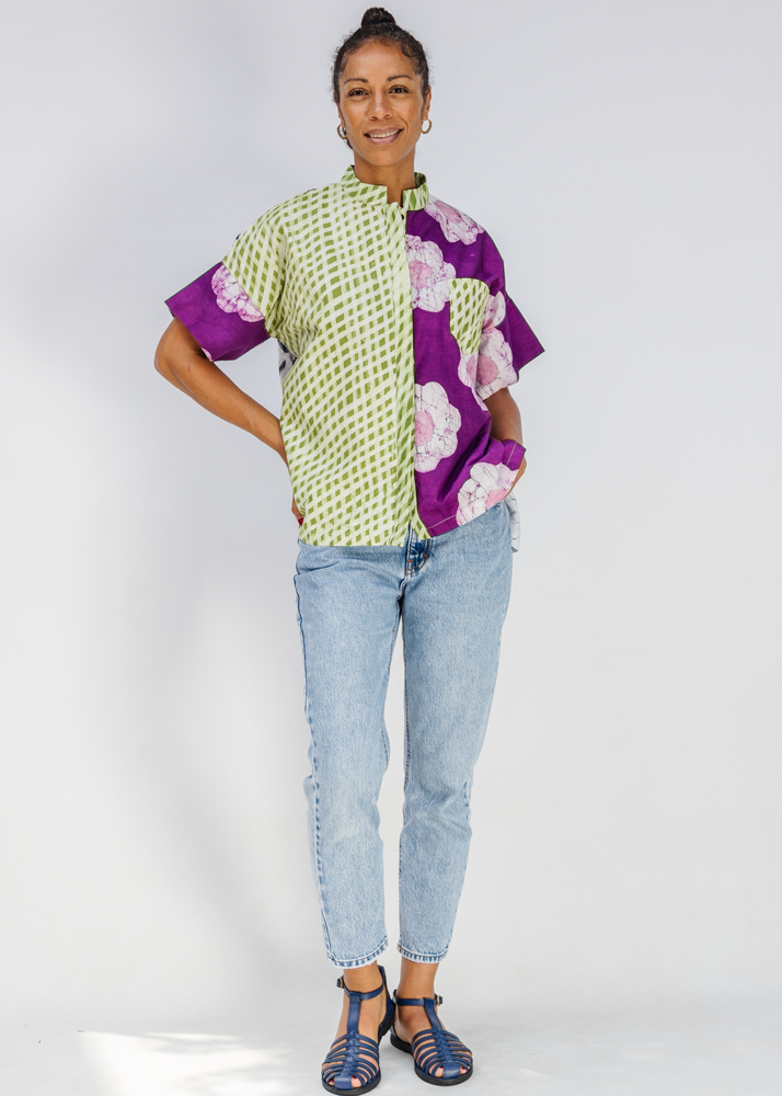Person wearing a colorful patterned shirt and jeans on a white background