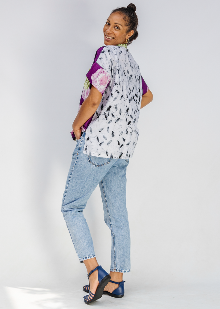 Woman wearing a patterned shirt and jeans on a white background
