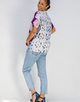 Woman wearing a patterned shirt and jeans on a white background