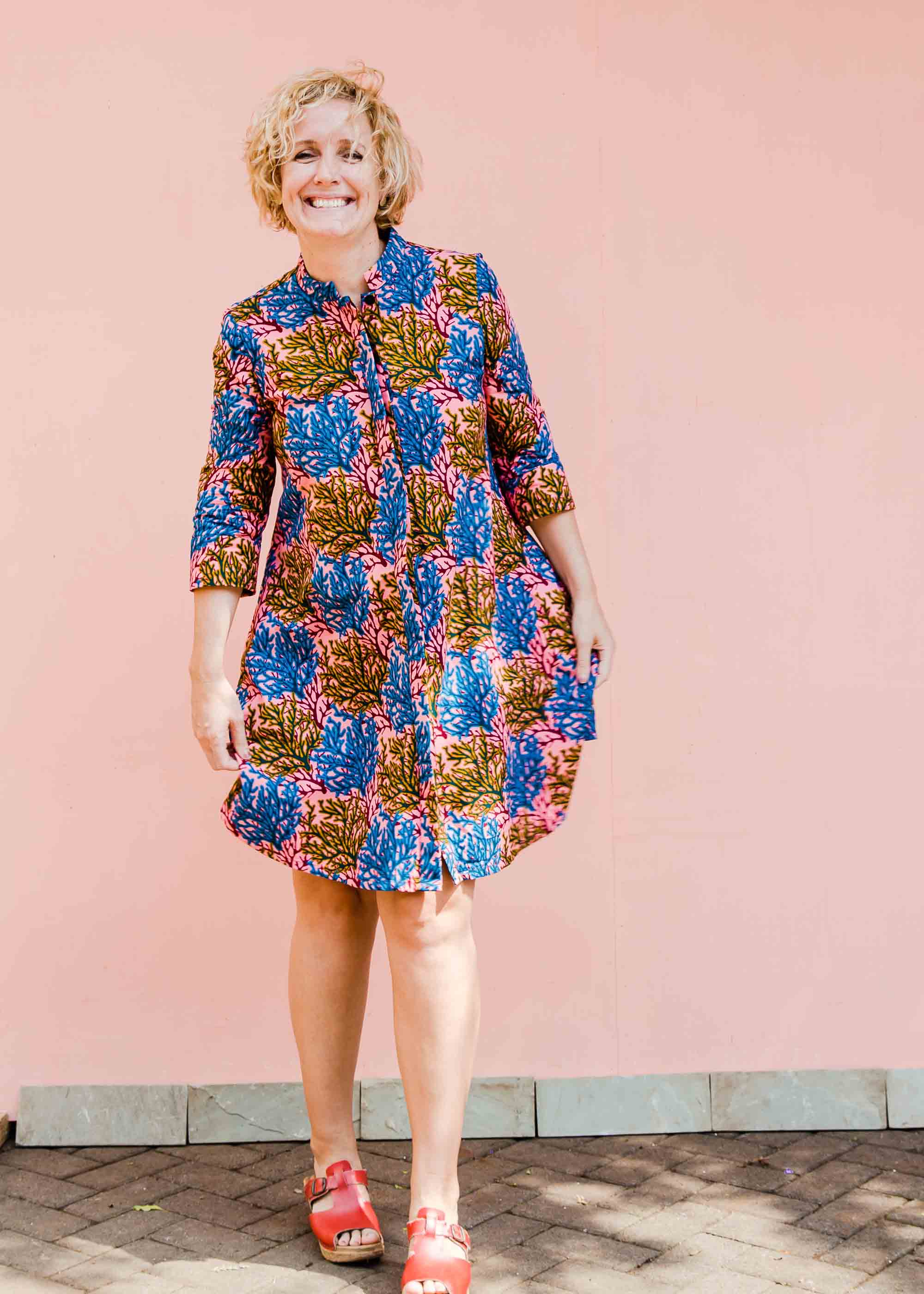 model wearing a  blue, yellow and pink coral print shirt dress 