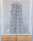 Display of white sleeveless dress with large black and purple floral print.