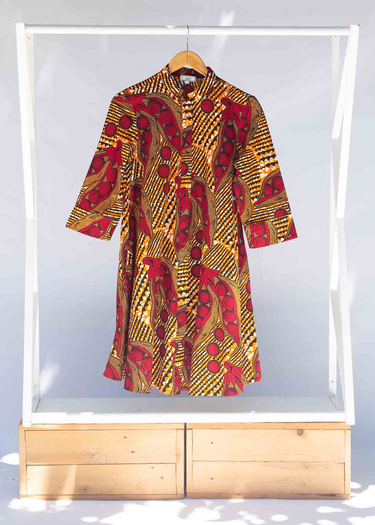 Display of brown dress with red snap pea print.