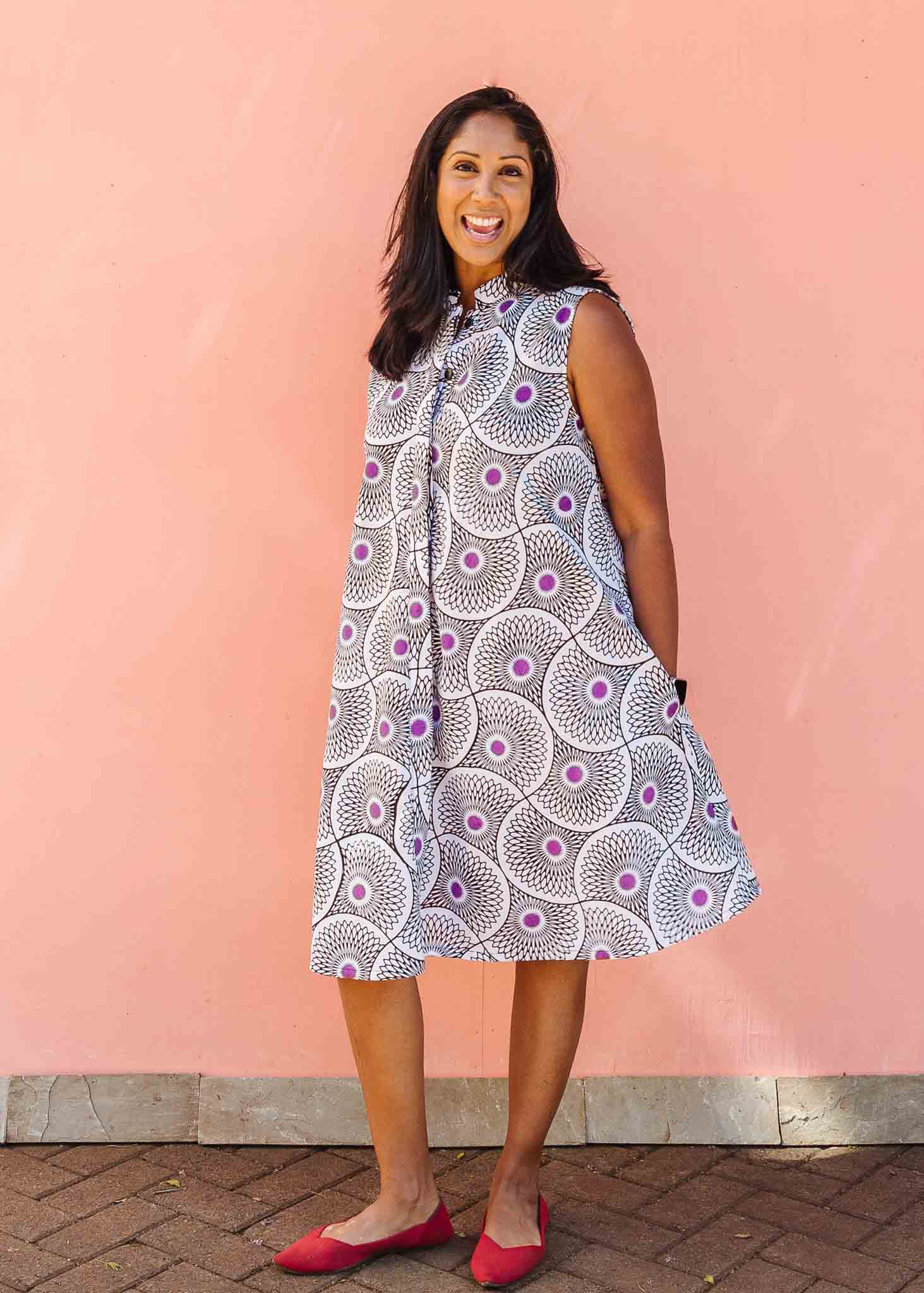 Model wearing white sleeveless dress with large black and purple floral print.