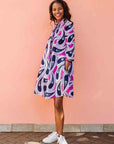 Model wearing purple and pink geometric print dress.