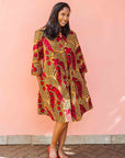 Model wearing brown dress with red snap pea print.