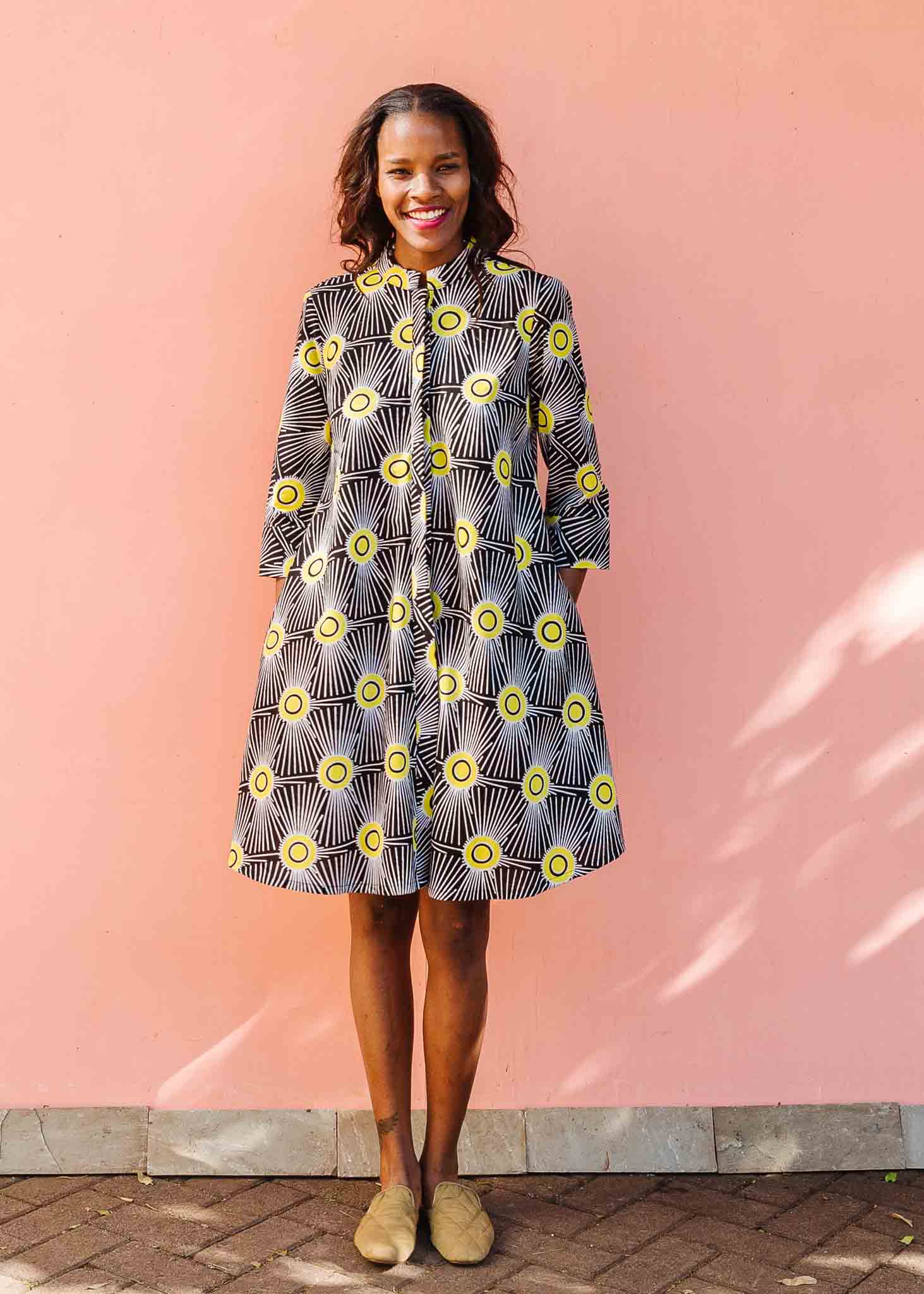 Model wearing black and white dress with yellow burst print.