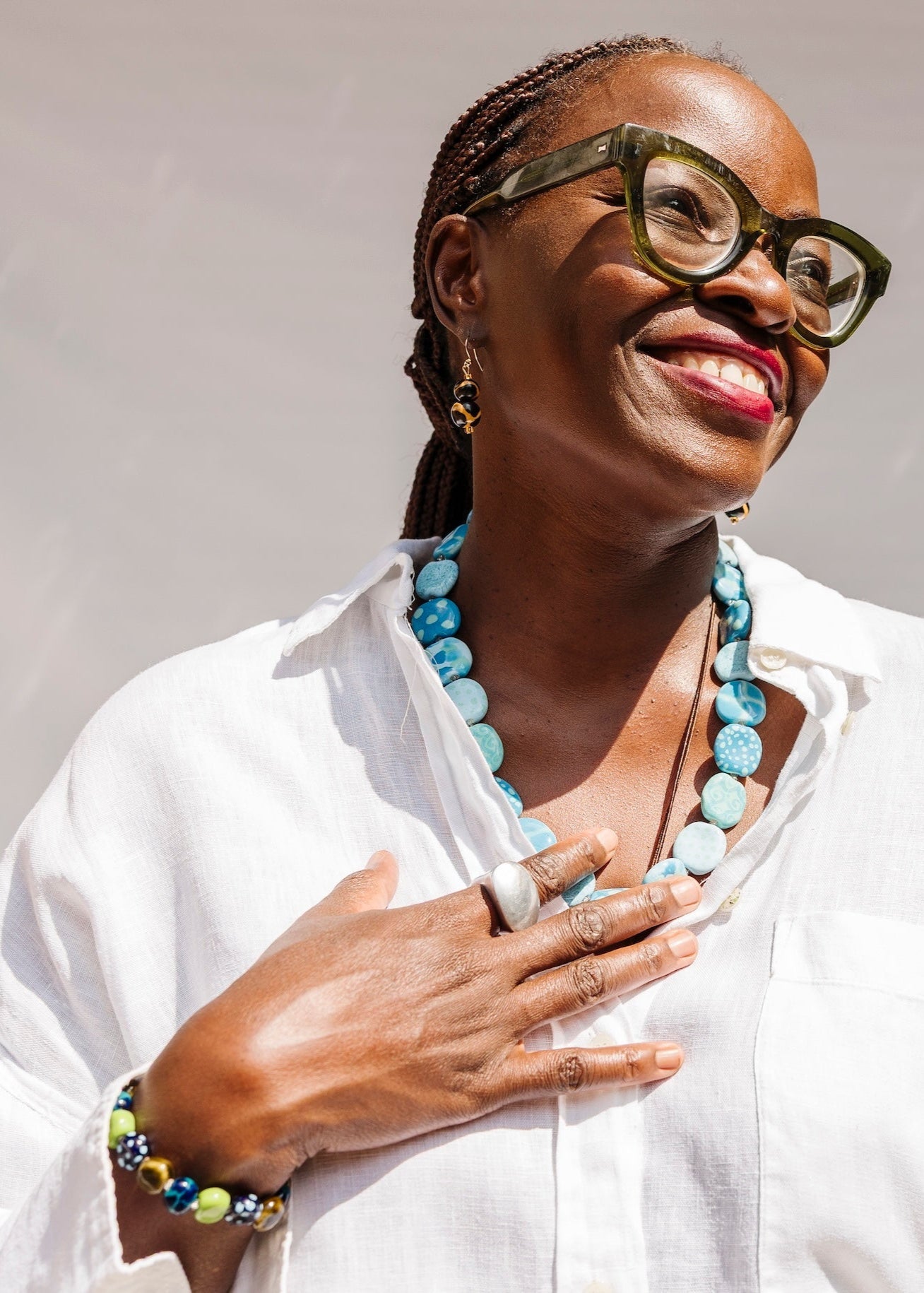 Close up shot of model wearing white shirt with blue necklace and ceramic accessories.