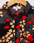 Display of black dress with beige flowers and red hearts 