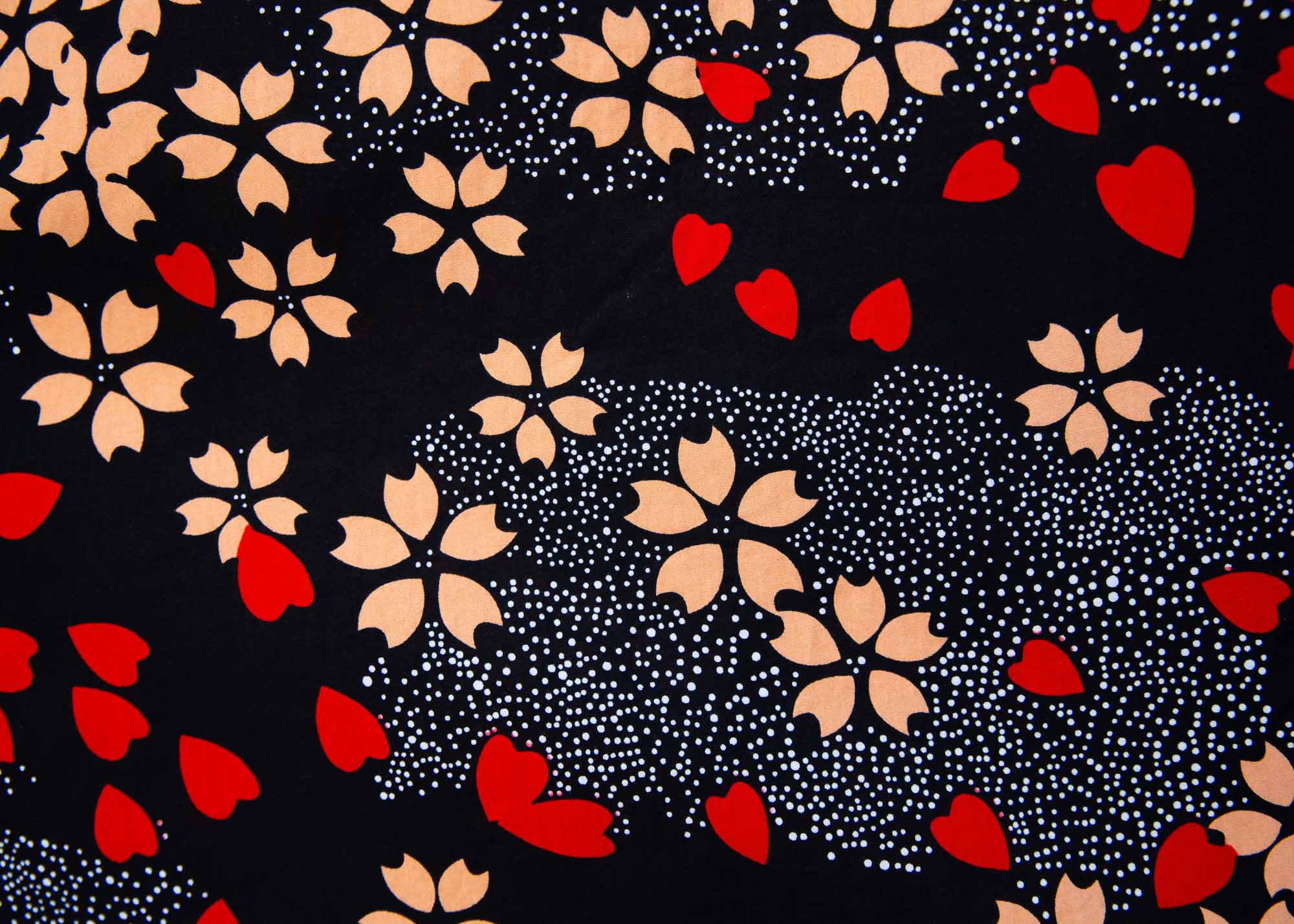 Close up display of black dress with beige flowers and red hearts