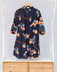 Display of black dress with orange, white and brown floral print